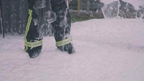 Crop firefighter in wet uniform standing in white foam while suppressing fire during rescue mission