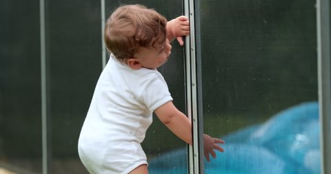Cute baby blocked by pool security fence protection, drowning prevention
