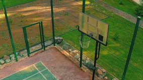 Top view of basketball player approaching, scoring hoop on basketball court outdoor in sunlight