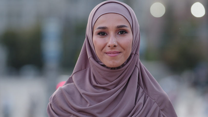 Close-up human female face portrait muslim girl young friendly smiling cute islamic woman student foreigner client wears hijab millennial arab lady standing outdoors looking at camera smile toothy Royalty-Free Stock Footage #1078457939