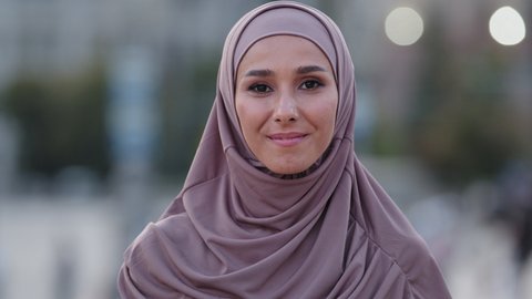 Close-up human female face portrait muslim girl young friendly smiling cute islamic woman student foreigner client wears hijab millennial arab lady standing outdoors looking at camera smile toothy