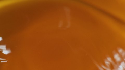 Water moves in a glass in slow motion. Abstract orange water background.