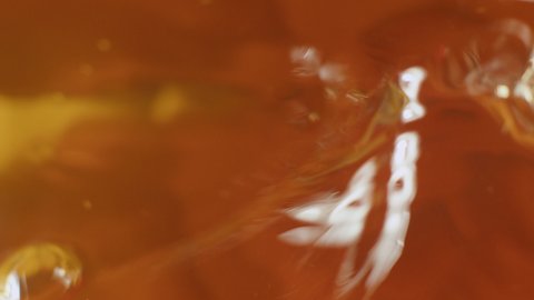 Water moves in a glass in slow motion. Abstract orange water background.