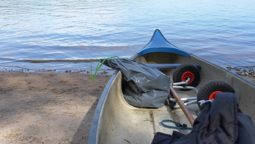 Handheld upward tilting view of tranquil water landscape from a canoe on the shore, in summer.