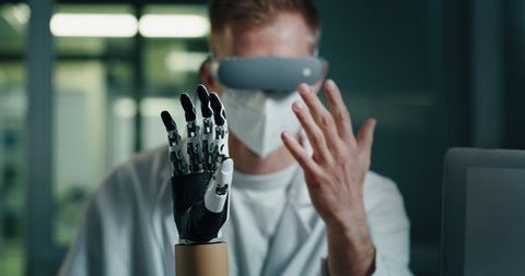 Cinematic shot of science engineer is controlling efficiency of latest innovative futuristic technology bionic hand prosthesis in modern laboratory.