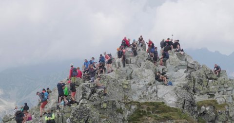 Crowd of tourists, hikers, on the narrow and rocky Rysy Peak (2500m), the highest peak in Poland, on the border with Slovakia. High Tatras, Poland - August 14, 2021.