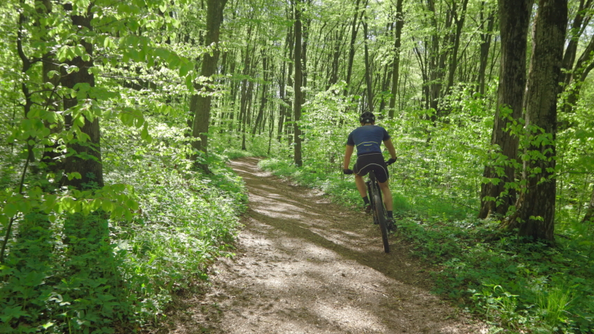 A cyclist is riding downhill in the forest. He is moving from side to side for better control. Training on an MTB bike. 4K  Royalty-Free Stock Footage #1078480439