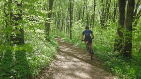 A cyclist is riding downhill in the forest. He is moving from side to side for better control. Training on an MTB bike. 4K  - Powered by Shutterstock - Get 15% off with code: PIKWIZARD15