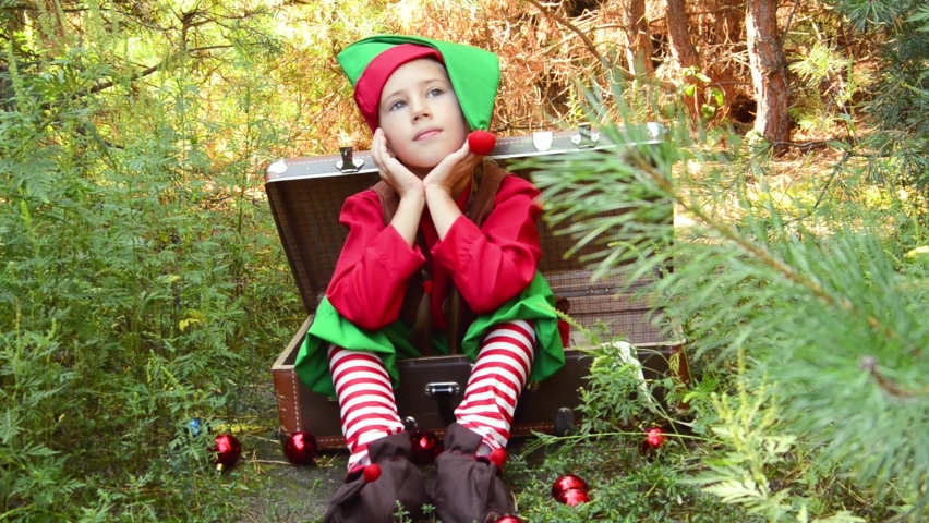 a girl elf sits in a suitcase with a smile on her face looking around