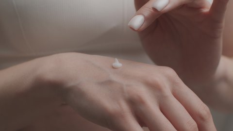 Female body care. Close up shot of young unrecognizable female applying organic moisturizing cream on hand skin, pampering palm, slow motion
