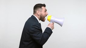 Side view portrait of young adult bearded businessman in black official style suit screaming at megaphone, making announcement, protest. Indoor studio shot isolated on gray background. - Powered by Shutterstock - Get 15% off with code: PIKWIZARD15