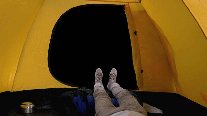 Camper lying inside open tent, view of legs in woolen socks against outside background, Full HD footage with alpha transparency channel isolated on black background
