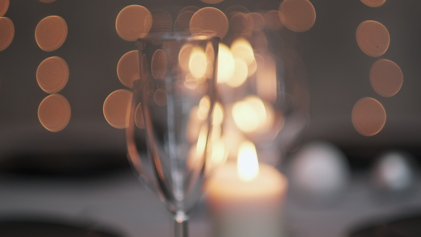 Festive served dining table. Beautiful dishes, tablecloths, wine glasses and gray plates. Candles and a garland in the background. Minimalistic dining room decor. Christmas.