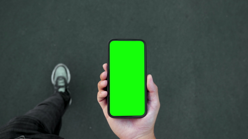 Young Man Walking and Use Green Screen Chroma Key Phone Point of View. Caucasian Person Hold in Hand Smartphone Mock-up and Watching Video Call, Copy Space Browsing. Go in Urban Mobile Phone Close-up | Shutterstock HD Video #1078492661