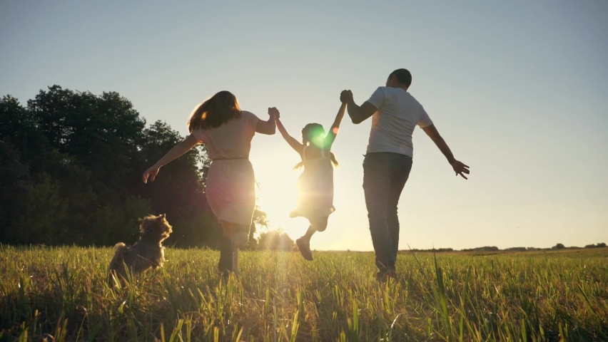 Happy family in park at sunset with pet. family has fun with child. Parents hold child by hands. Helping hand of parents. Walking happy family with pet in park at sunset. Happy family with dog Royalty-Free Stock Footage #1078493219