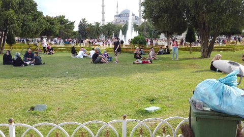 Istanbul, Turkey - July 2021: Tourists resting around Sultanahmet square park with Blue mosque in the background