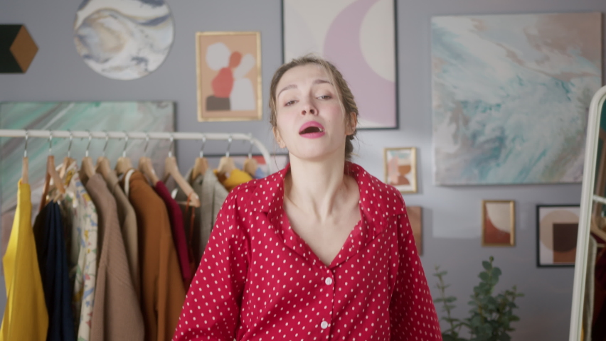 Portrait of small business owner dancing, beautiful woman trying on dress, posing in clothes concept store, stylist shopping assistance, woman choosing clothes in wardrobe. Work after covid lockdown.