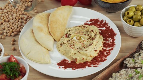 Israeli cuisine. Hummus decorated with paprika and pita on plate close-up. National Food, middle eastern culture. Vegan chickpea puree snack. Appetizer made from mashed chickpeas. 
