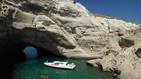 Aerial drone video of beautiful volcanic open cave of Sykia a geological phenomenon - leaving an opening for small inflatable boat to enter in South West of Milos island, Cyclades, Greece
