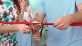Man and Woman Cut the Red Ribbon in Honor of the Opening of a New Store, While Many Unrecognizable People are Applauding in the background. Married Couple Opens Their Own Business. Slow motion. - Powered by Shutterstock - Get 15% off with code: PIKWIZARD15