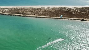 Birds yes view of man engaged in extreme sports by riding on water board with parachute on wave, Alvor, Portugal, Europe. Male athlete kitesurfing on coast of Atlantic ocean, 4k footage