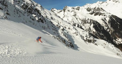 Slow motion deep snow powder skiing in beautiful long ski turns with amazing alpine mountain view. Freeride skiing after a long and hard ski tour in the mountains of Tyrol Austria. Coloreful ski dress