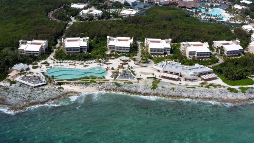 Beautiful aerial drone view of the tropical coastline of playa del carmen with large vacation resorts with pools and bars in Riviera Maya, Mexico on a warm sunny summer day.