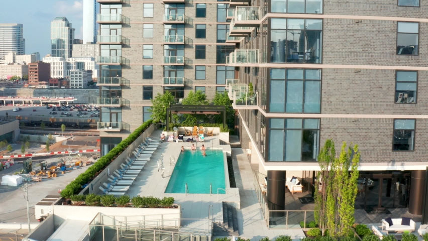Rooftop pool at upscale residential urban apartment building in USA city. Rising aerial. Royalty-Free Stock Footage #1078511498