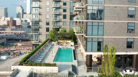 Rooftop pool at upscale residential urban apartment building in USA city. Rising aerial.