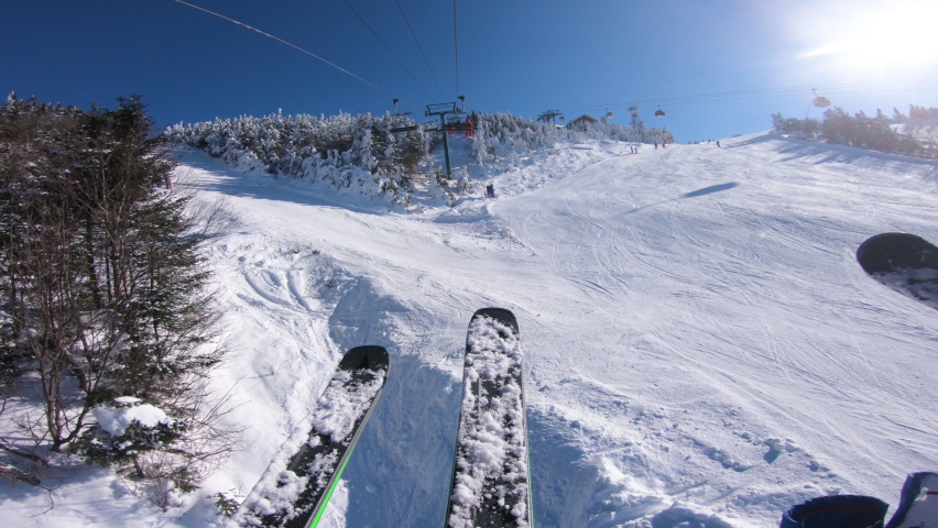 Ski holidays. Ski lift and gondola. First person view POV with skis. Skiing on snow slopes in the mountains, People having fun on the slopes on a snowy day - Winter sport and outdoor activities Royalty-Free Stock Footage #1078512380