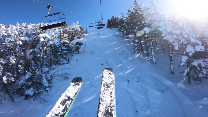 Ski holidays. Ski lift and gondola. First person view POV with skis. Skiing on snow slopes in the mountains, People having fun on the slopes on a snowy day - Winter sport and outdoor activities