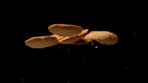 Super slow motion of bunch of cookies flying on black background.