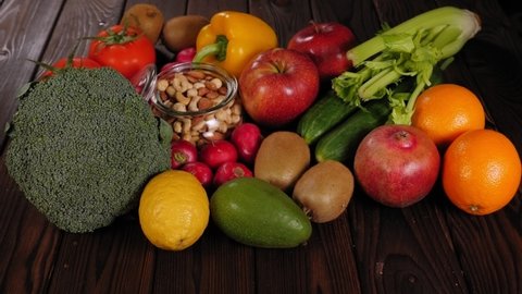 Close-up of many different fruits and vegetables on a wooden table, a woman's hand holding a blood sugar meter to measure blood sugar with a good result.
