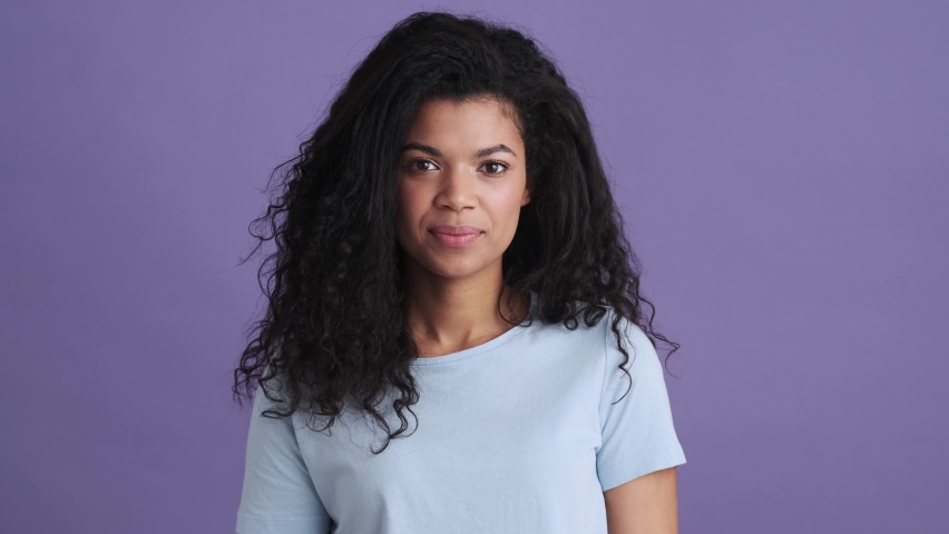A sad african woman in a t-shirt coughing in a purple studio