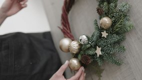 Women's hands collect a Christmas wreath from branches and fir trees. Spruce balls and wooden stars. Decoration for Christmas or New Year. Floral workshop. Vertical video