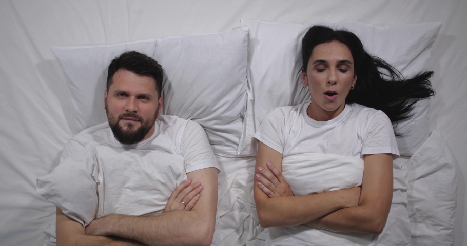 Top view of Caucasian couple quarelling in bed with white sheets. High angle shooting. Man and woman argue, take offense at each other and turn away in different directions Royalty-Free Stock Footage #1078541597