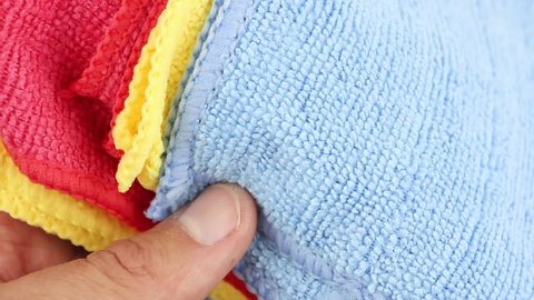 hands sorting colored microfiber dusting cloths, water absorbing synthetic fabric, close-up view, household cleaning equipment