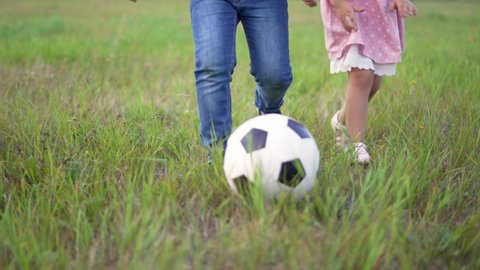 Happy family of children run across field. Group of children are playing with soccer ball. Happy family in park.Ball game in park. Family soccer game. Happy children in park run with ball.Happy family