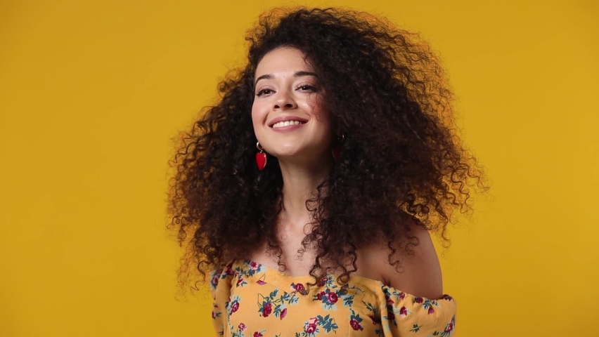 Magnificent overjoyed excited jubilant happy young latin curly woman 20s wears casual flower dress dance waving fooling around have fun enjoy play fluttering hair isolated on plain yellow background Royalty-Free Stock Footage #1078555178