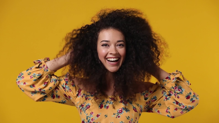 Magnificent overjoyed excited jubilant happy young latin curly woman 20s wears casual flower dress dance waving fooling around have fun enjoy play fluttering hair isolated on plain yellow background Royalty-Free Stock Footage #1078555178