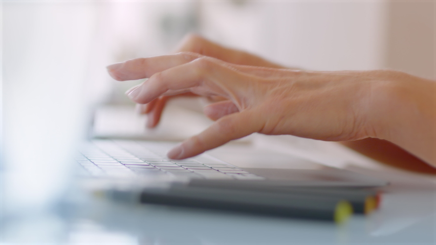 Lateral Dolly of Female Hands Typing on Keyword and Scrolling on a Track Pad. Laptop. Detail Shot. Shallow Depth of Field. White Desktop With Colorful Office Elements. Royalty-Free Stock Footage #1078557728