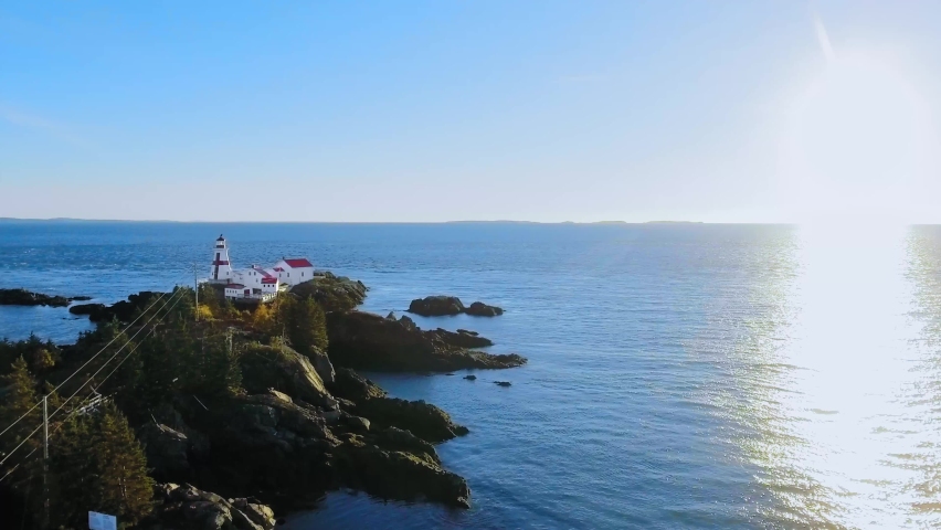 Aerial camera appoaches the Head Harbour Lightstation on a sunny evening, drone shot from Campobello Island, New Brunswick, Canada Royalty-Free Stock Footage #1078560131