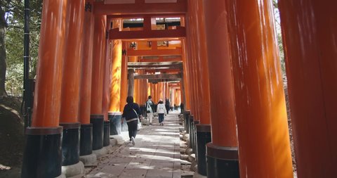 Kyoto, JAPAN - Apr 2 2021 : Tourists walking through the Senbon Torii (thousands of vermilion torii gates) of Fushimi Inari-taisha complex. Translation : votive offering