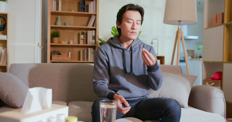asian man takes medicine or vitamin by water in living room at home Royalty-Free Stock Footage #1078572794