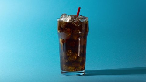 UKRAINE, KIEV - SEPTEMBER 02, 2021: Glass of cola with ice, can and bottle of Coca-Cola replace each other on blue background. from dark to light effect. Looped Stop motion animation