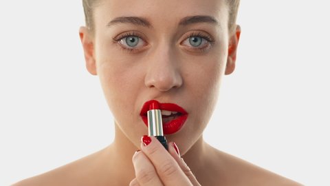 Woman paints lips with luxury cosmetics. Matching the shade of suitable lipstick. Girl looking at the camera, turns head full face. Girl with cleanskin and bright red lips. Concept of cosmetics store.