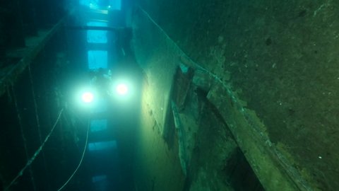 Scuba diver photographer swims inside of the shipwreck Swedish ferry MS Zenobia. Wreck diving. Mediterranean sea, Cyprus
