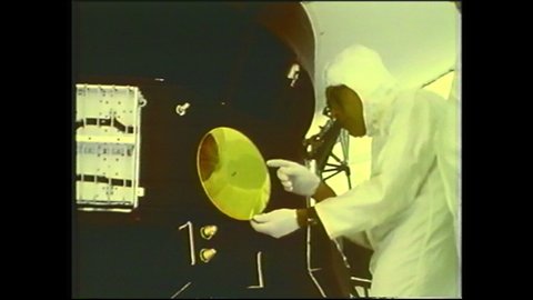 1990s: Tool spraying golden spinning record. Golden record and case sitting next to booklet. Golden record. Man in cleansuit affixing golden record case to side of space probe.
