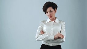 Young adult business woman with bob haircut wearing formal silk shirt and red lipstick posing for video clip in studio on white background. Friendly businesswoman with arms crossed on chest