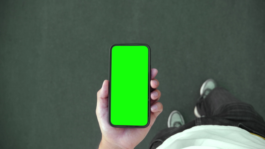 Young Person Walk and Use Green Screen Chroma Key Smartphone Top Point of View. Caucasian Man Hold in Hand Phone Mock-up and Watching Video Call, Copy Space Browsing. Go in Urban Cellphone Close-up 4k Royalty-Free Stock Footage #1078599788